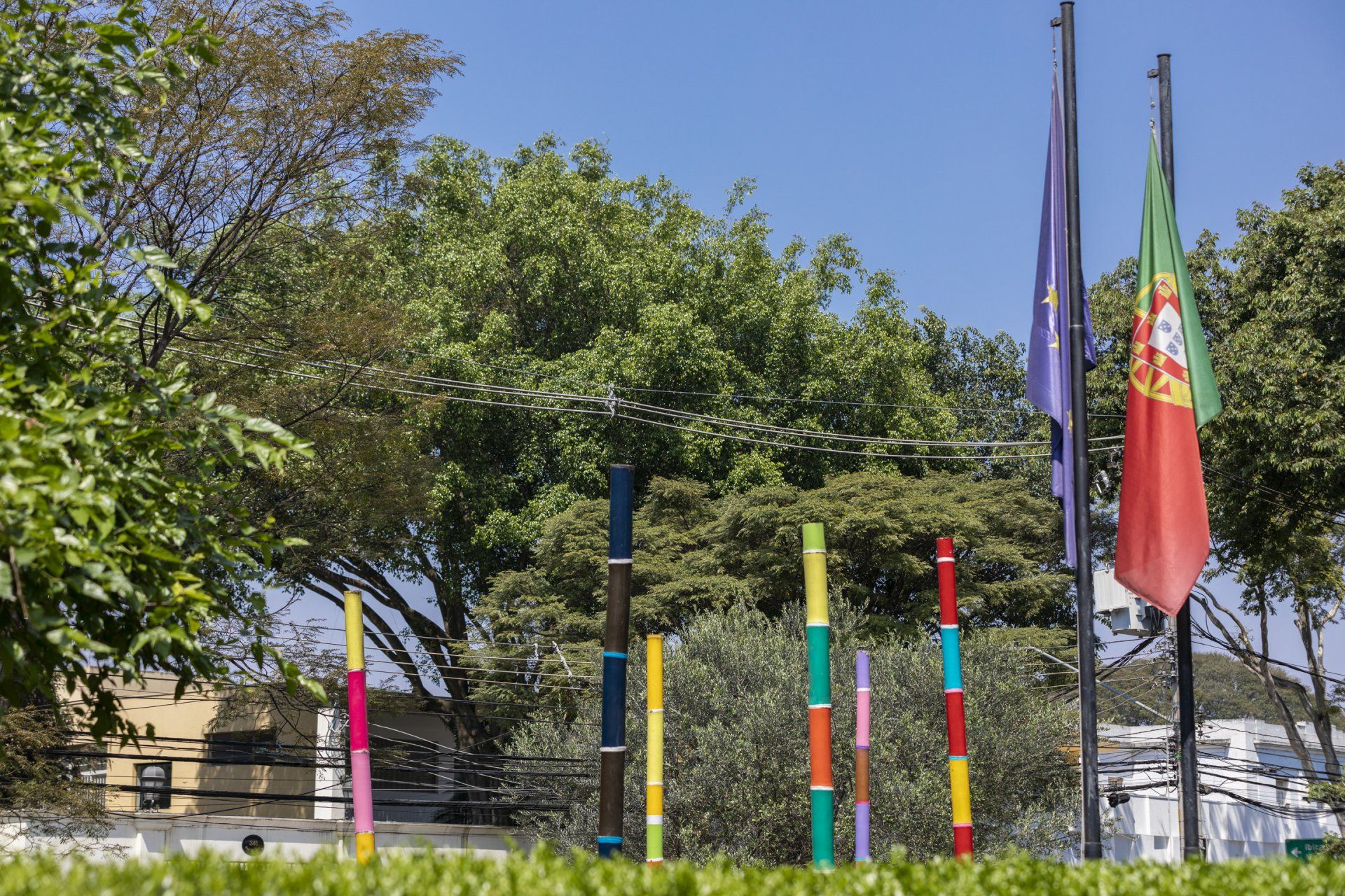 Uma fileira de postes coloridos em um parque com árvores ao fundo.