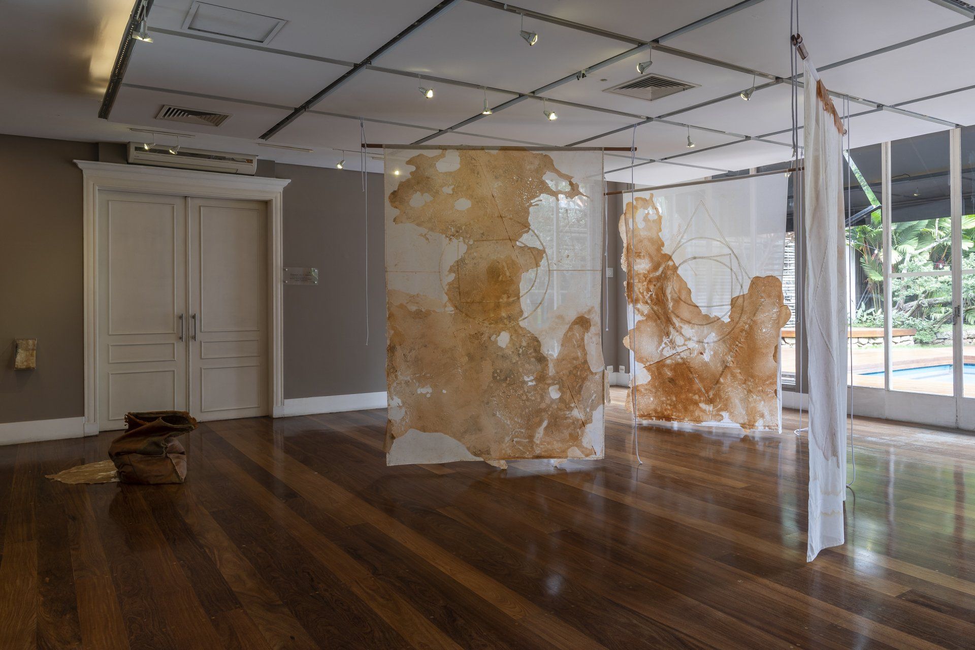 Uma sala ampla com piso de madeira e muitas pinturas na parede.