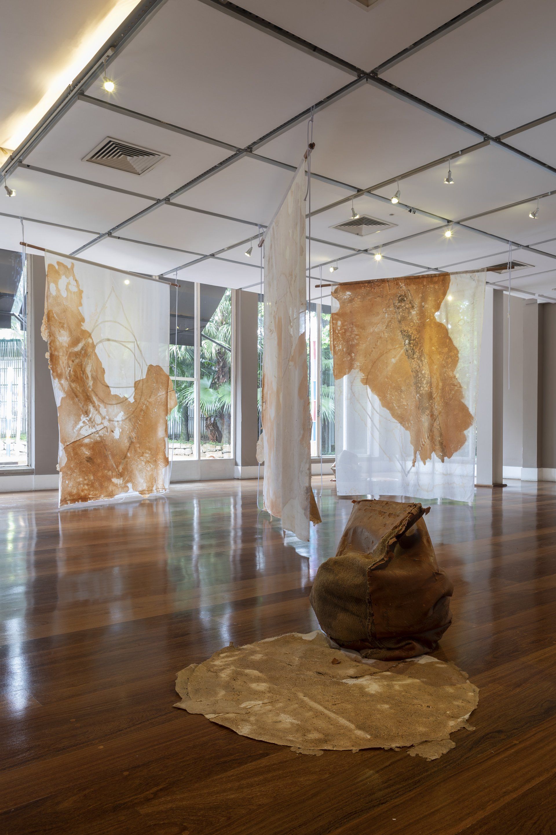 Uma sala ampla com piso de madeira e muitas pinturas nas paredes.