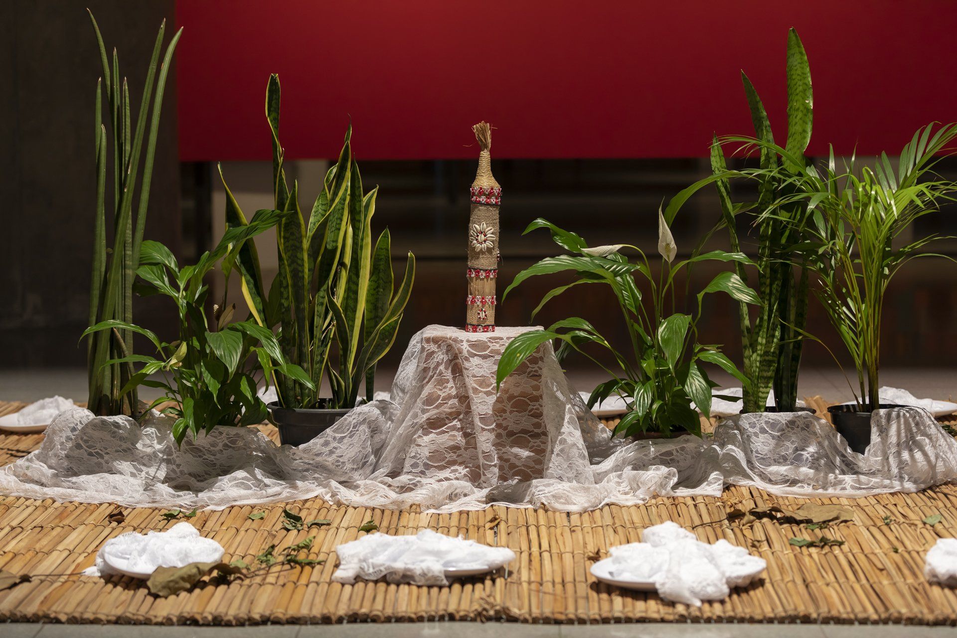 Uma mesa com vasos de plantas e uma estátua.