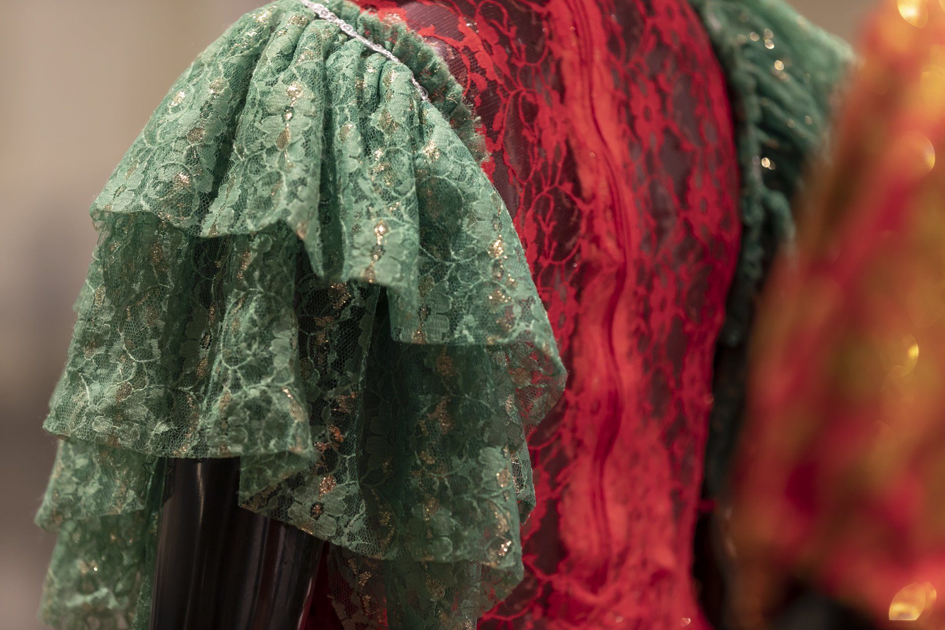 Um close de um vestido de renda vermelho e verde com babados nas mangas.