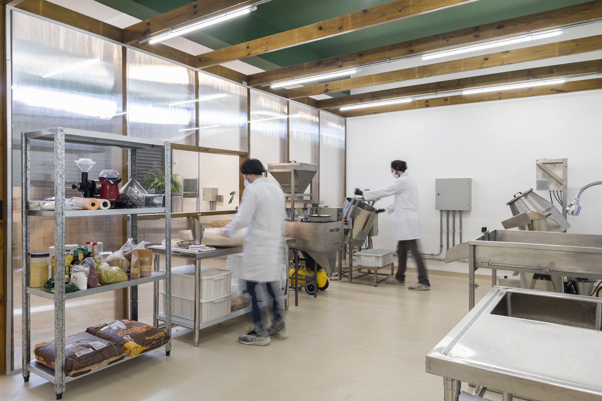 Dois homens de jaleco branco trabalham em uma cozinha.