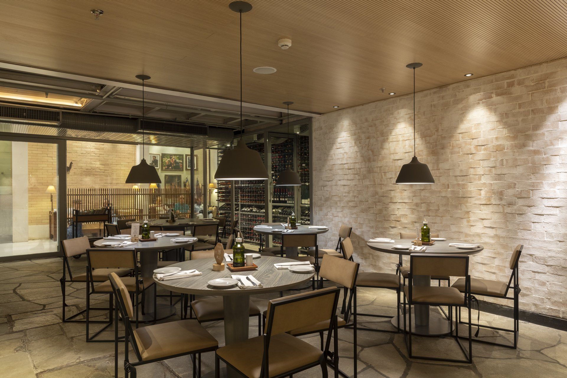 Um restaurante com mesas e cadeiras e uma parede de tijolos.