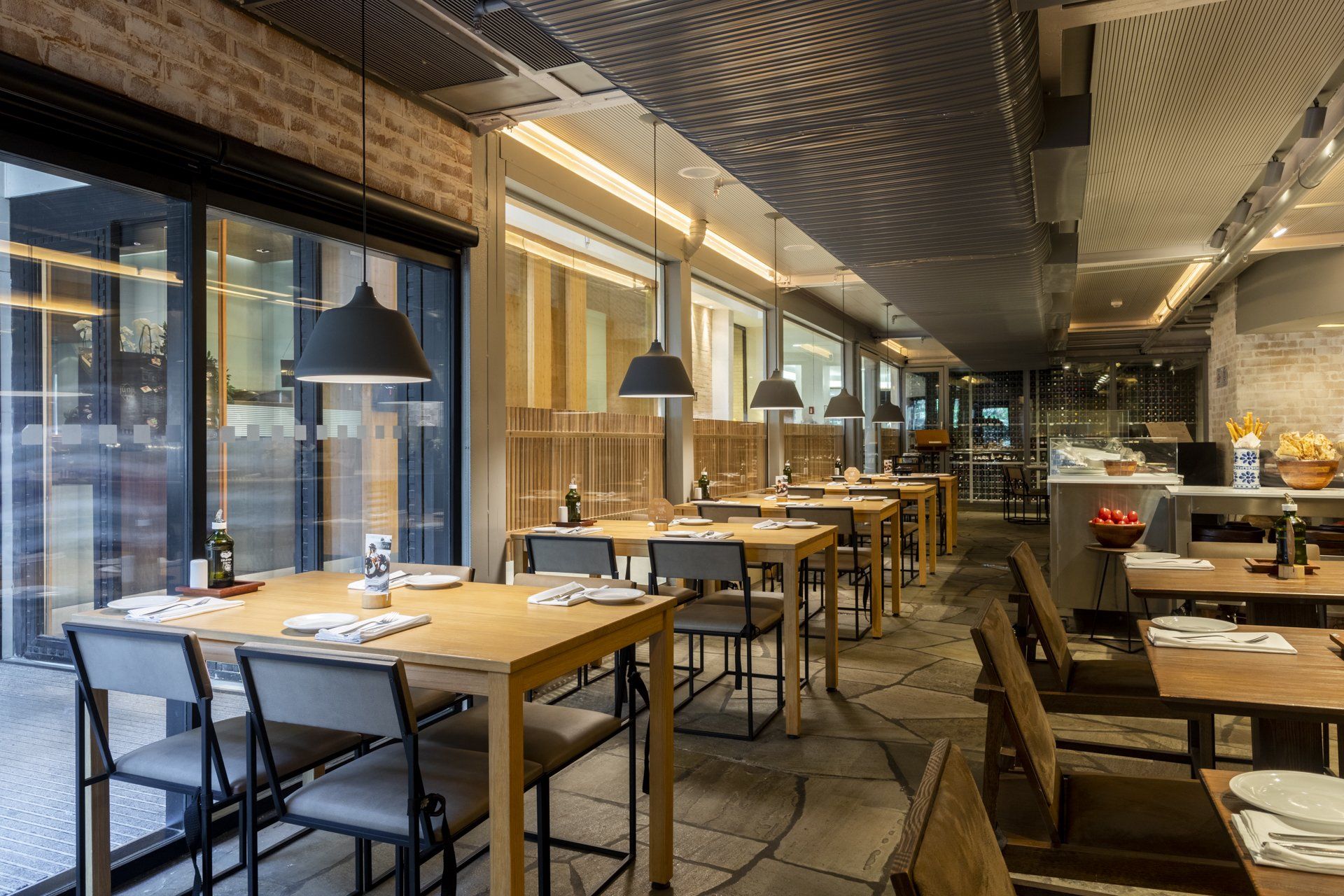 Um restaurante com mesas e cadeiras e muitas janelas.
