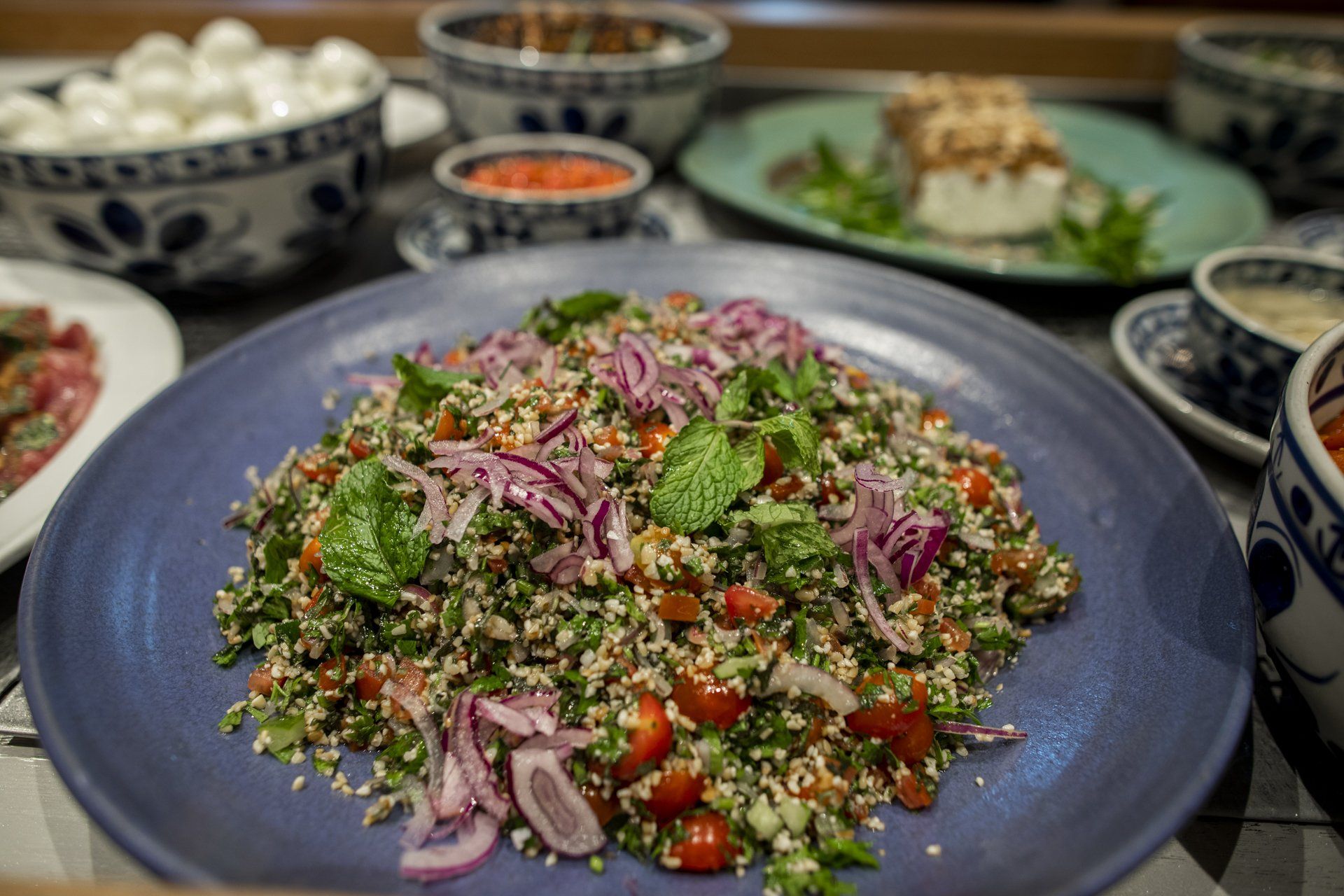 Um prato azul coberto com uma salada de legumes sobre uma mesa.