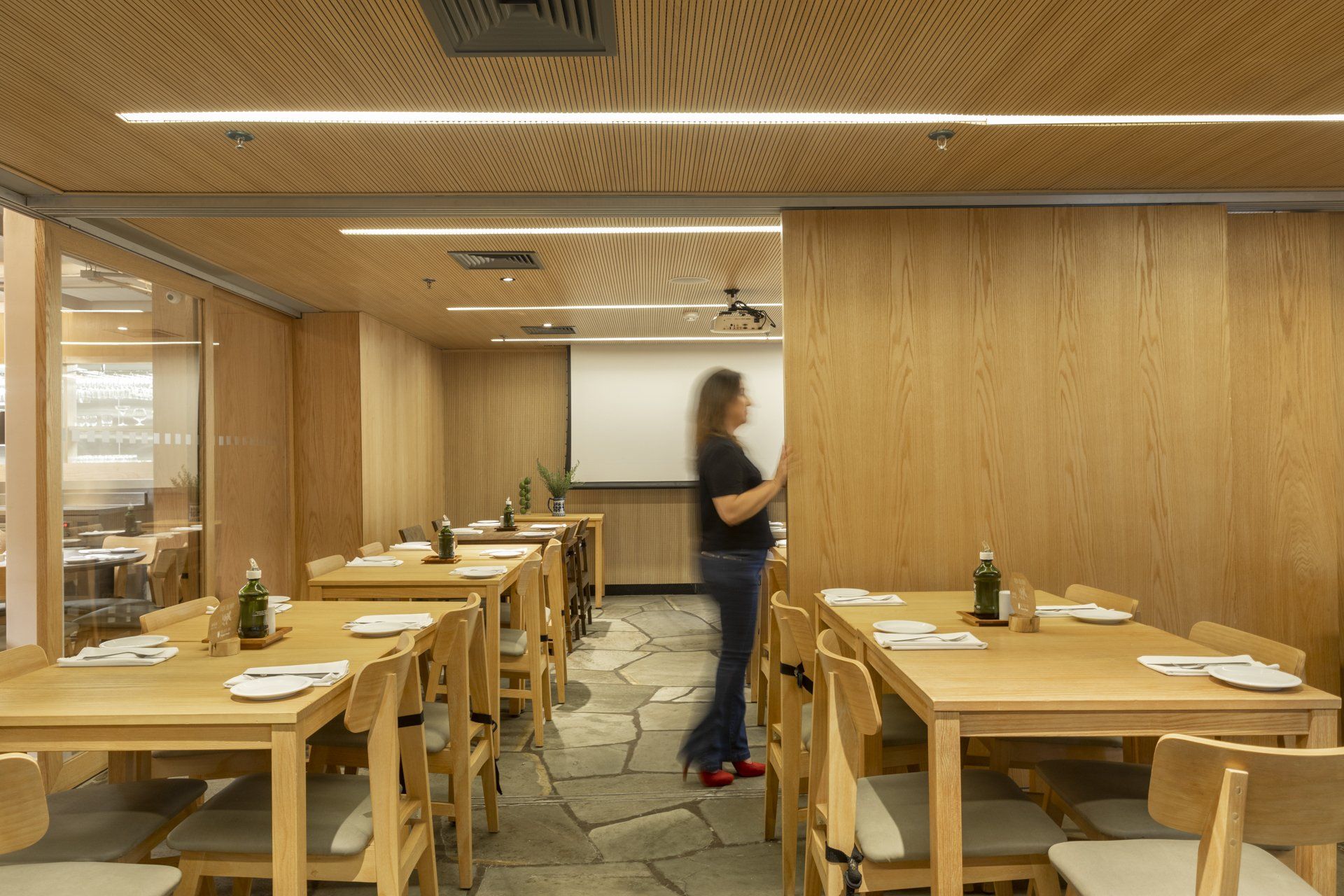 Uma mulher está em um restaurante com mesas e cadeiras.