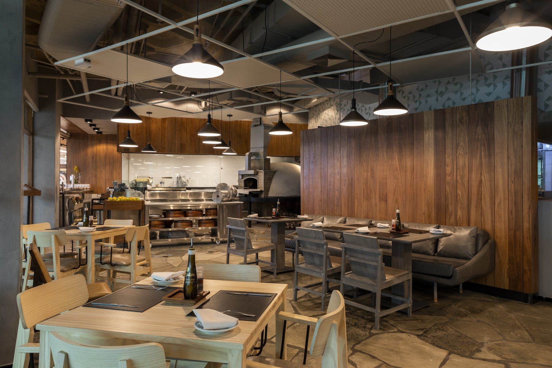 Um restaurante com mesas e cadeiras e uma cozinha ao fundo.