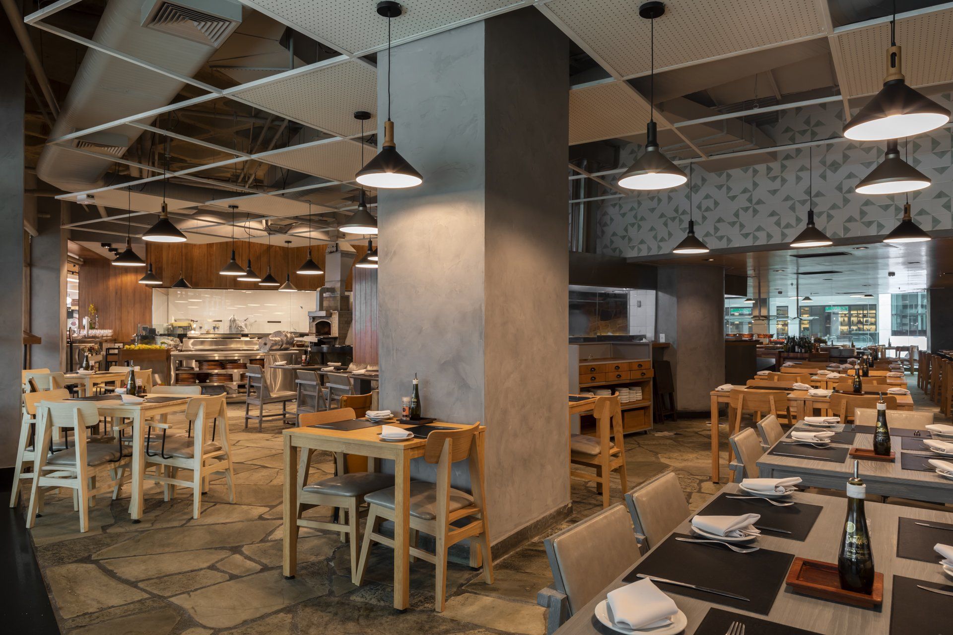 Um restaurante com mesas e cadeiras e uma cozinha ao fundo.