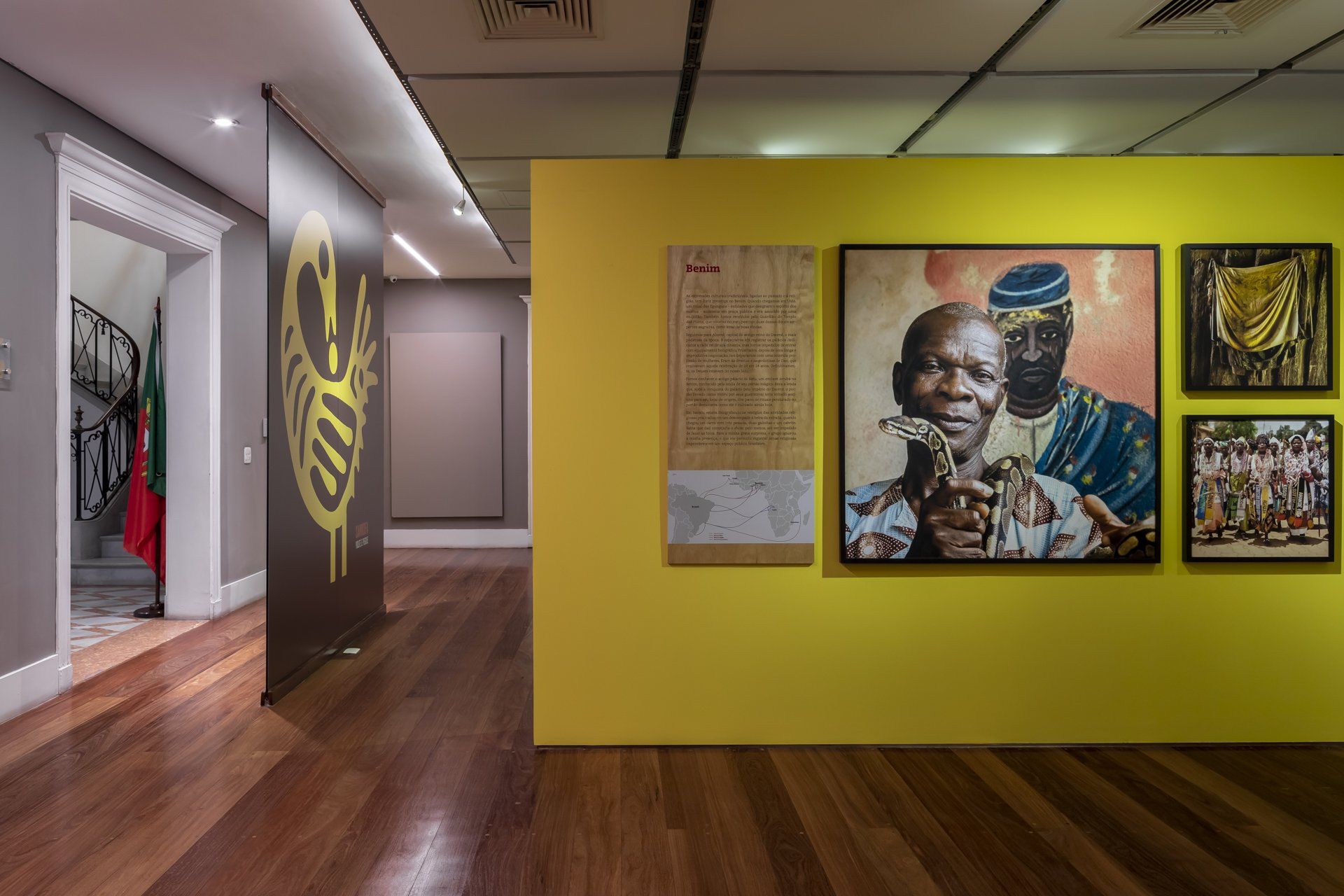 Uma sala com piso de madeira e uma parede amarela com pinturas.