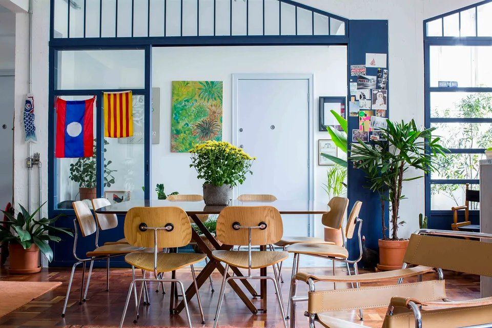 Uma sala de jantar com mesa, cadeiras e plantas.