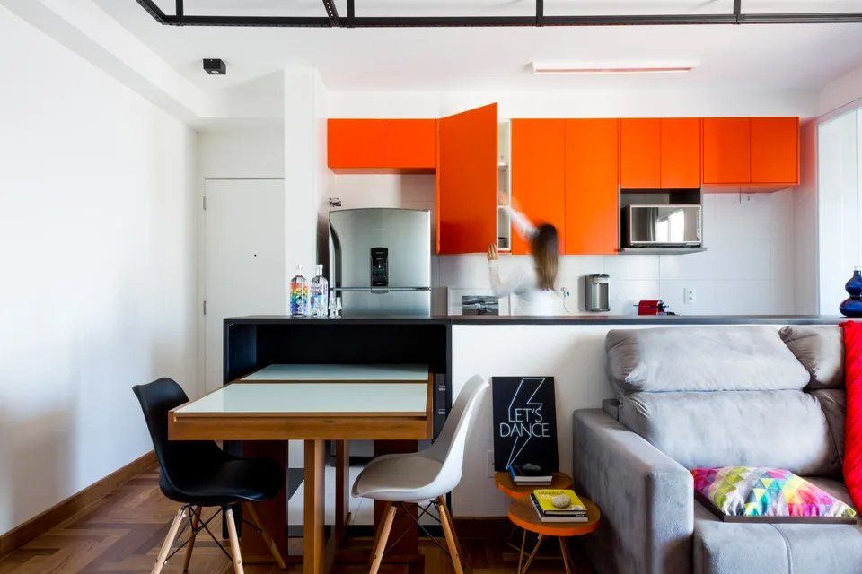 Uma sala de estar com armários laranja e mesa e cadeiras