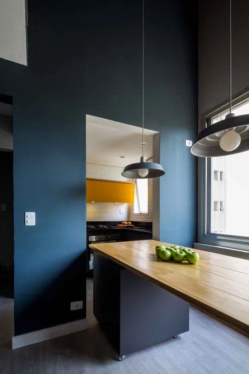 Uma cozinha com paredes azuis e uma mesa de madeira com maçãs