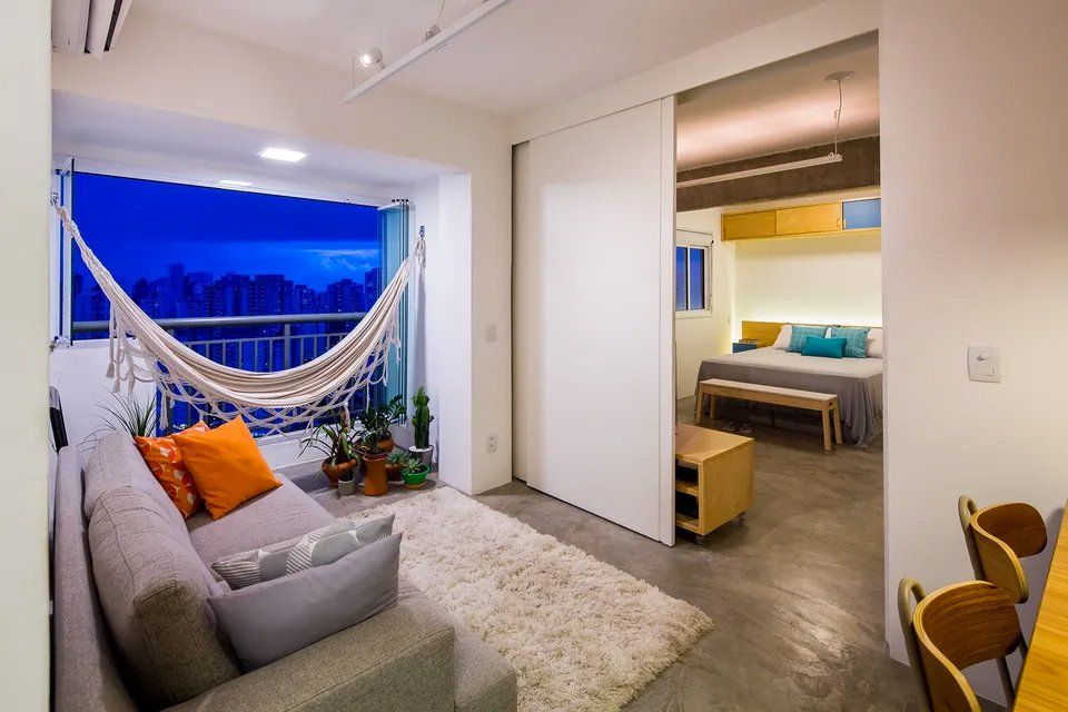 Uma sala com sofá, cadeiras, mesa e rede.