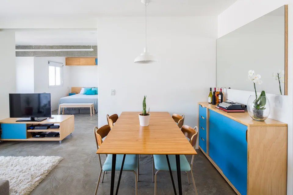 Uma sala de jantar com mesa e cadeiras e uma televisão.