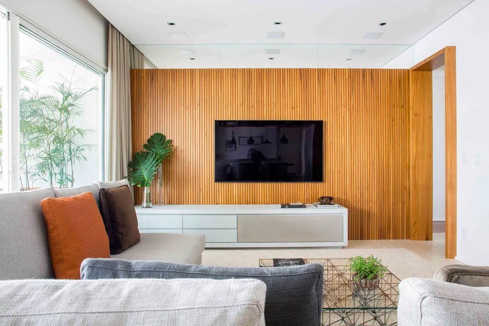 Uma sala de estar com parede de madeira e uma TV de tela plana na parede.