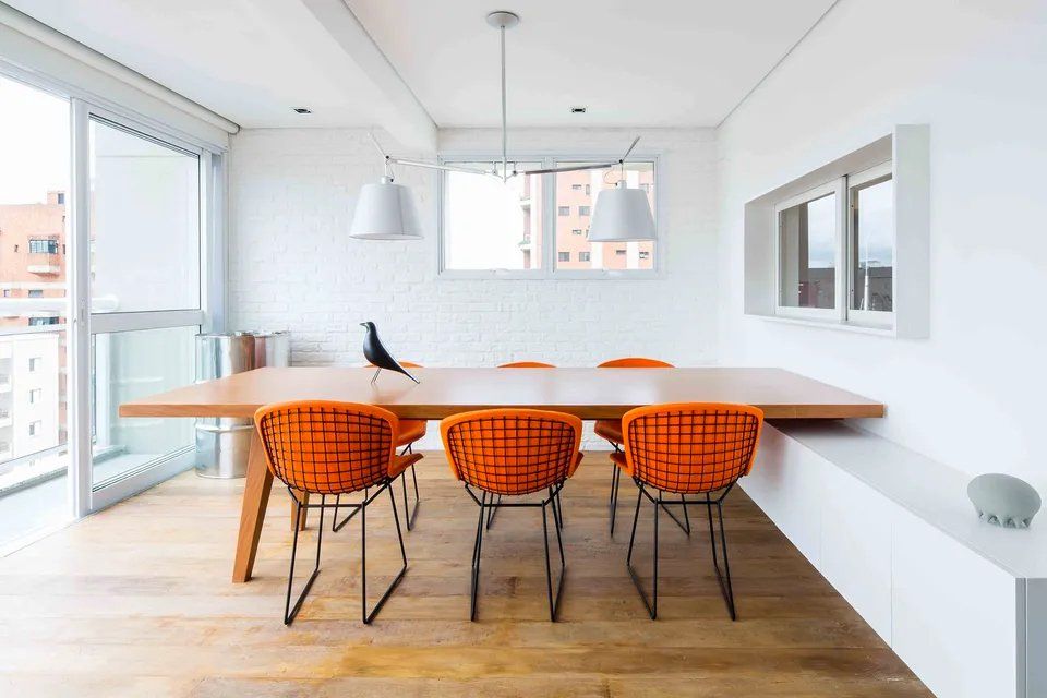 Uma sala de jantar com mesa de madeira e cadeiras laranja.