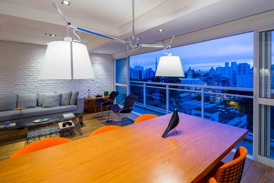 Uma sala de estar com mesa e cadeiras grandes e vista para a cidade.