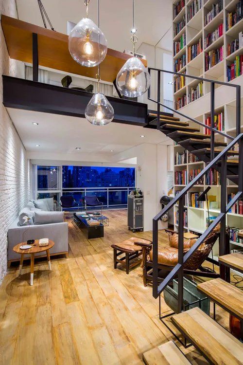 Uma sala com escada que dá acesso ao segundo andar.