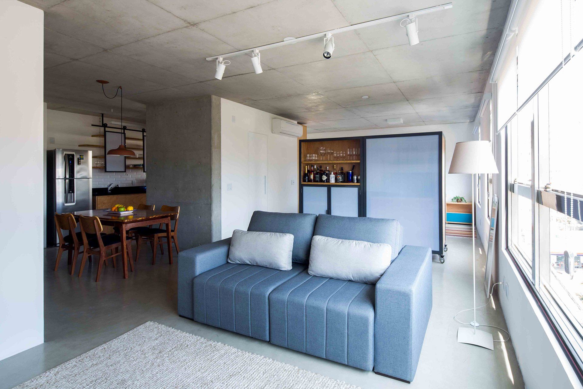 Uma sala com sofá azul e tapete branco.