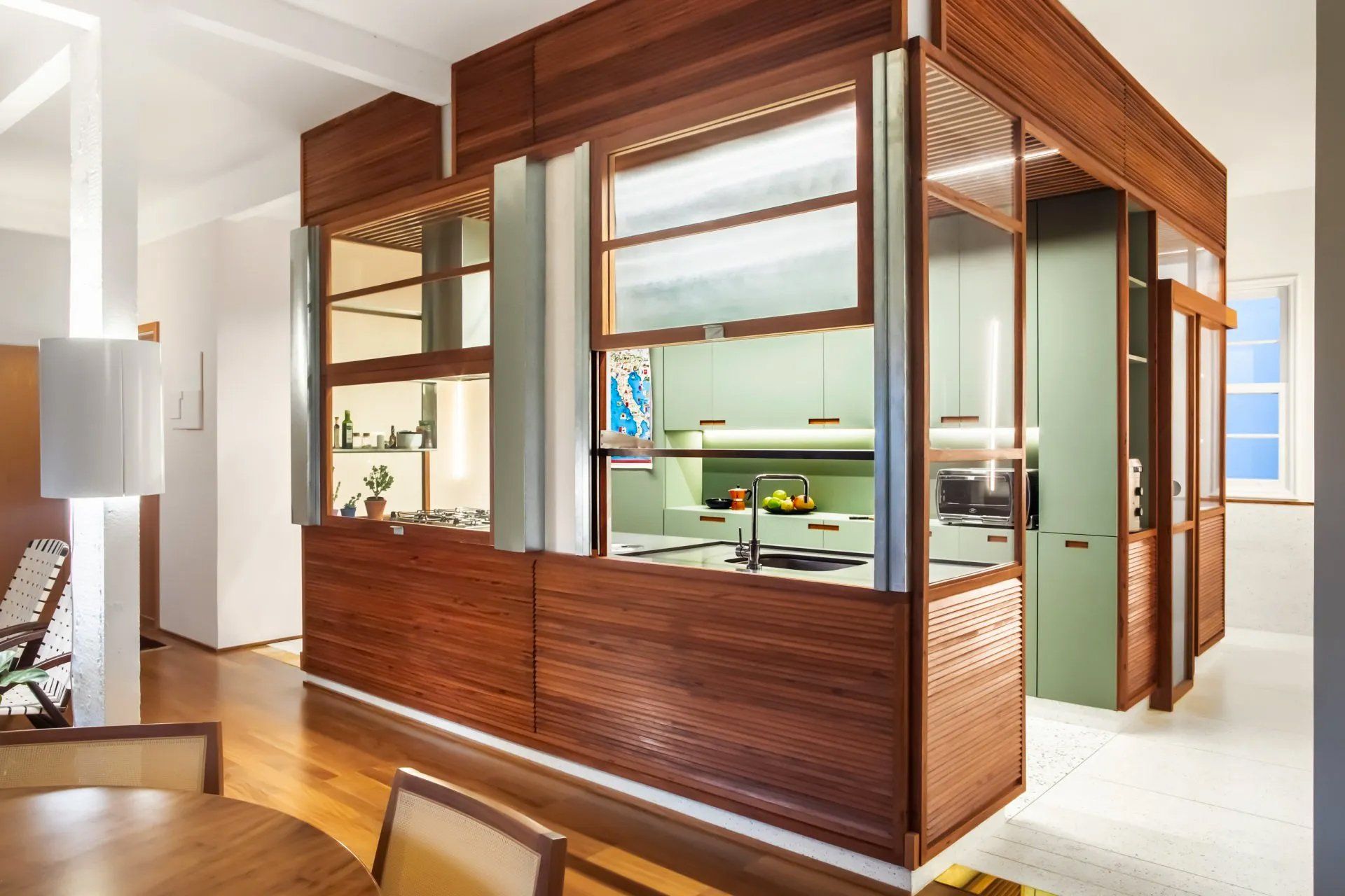 Uma sala de jantar com mesa e cadeiras e uma cozinha ao fundo