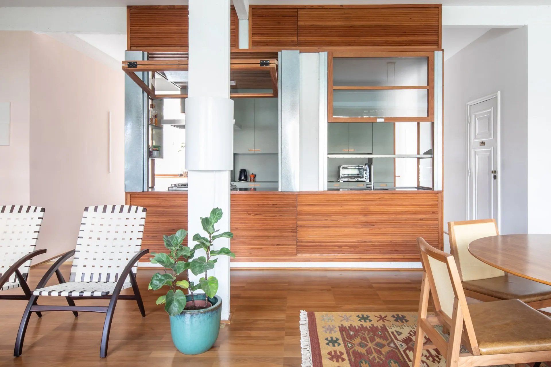 Uma sala de estar com mesa e cadeiras e um vaso de plantas
