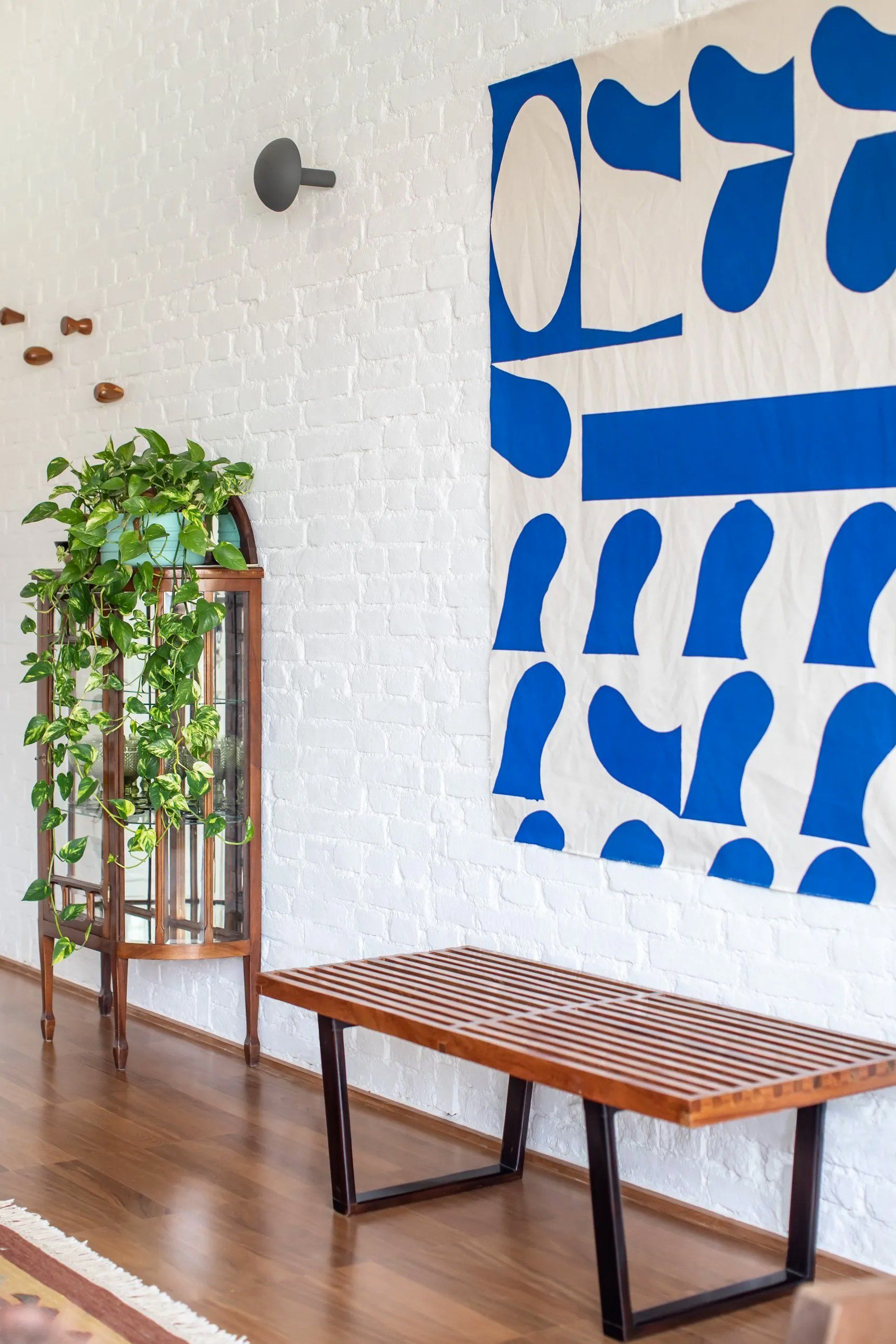 Uma sala com banco de madeira e uma grande pintura azul e branca na parede.