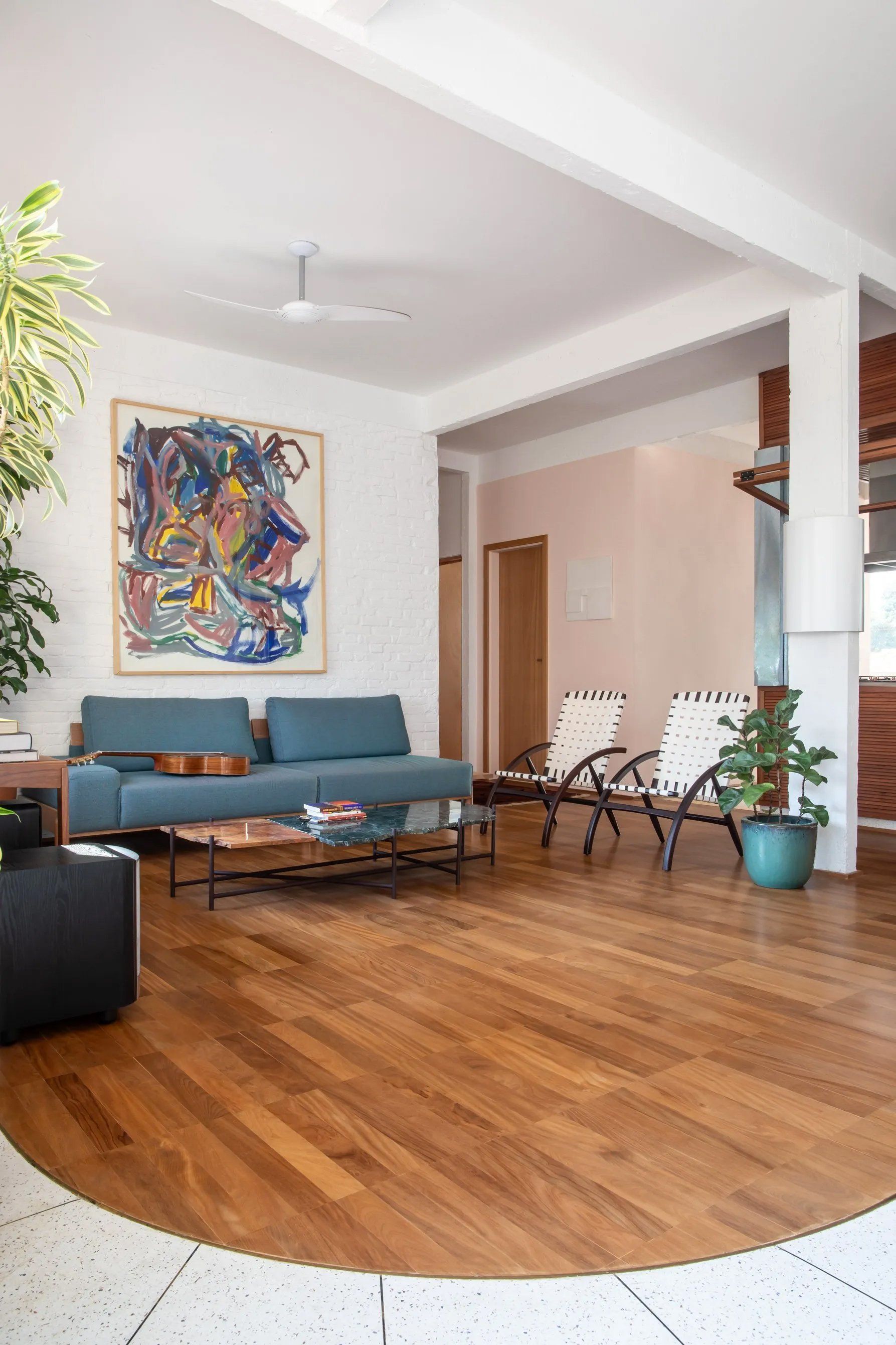 Uma sala com sofá, cadeiras, mesa de centro e um quadro na parede.