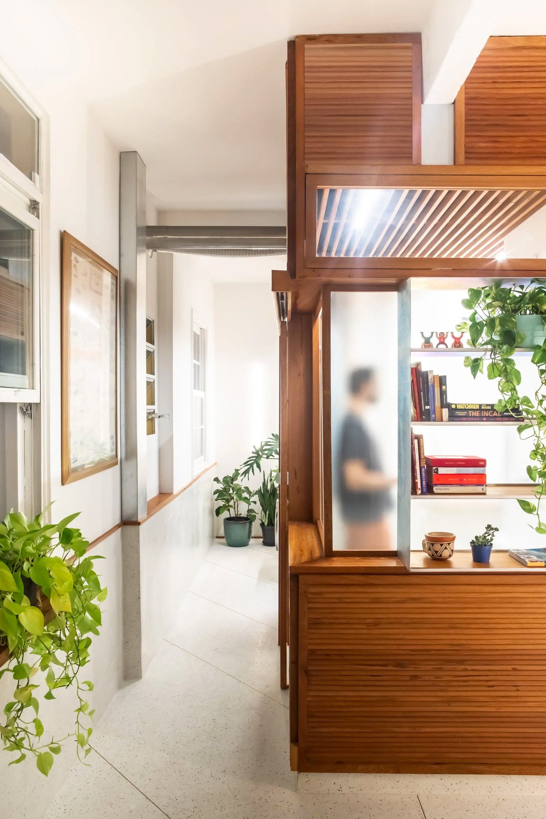Um homem está parado em um corredor entre dois cômodos de uma casa.