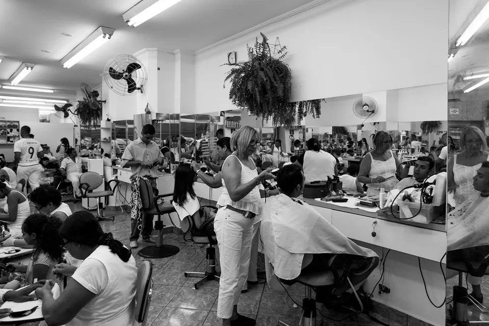 Uma mulher está cortando o cabelo de um homem em um salão de cabeleireiro.