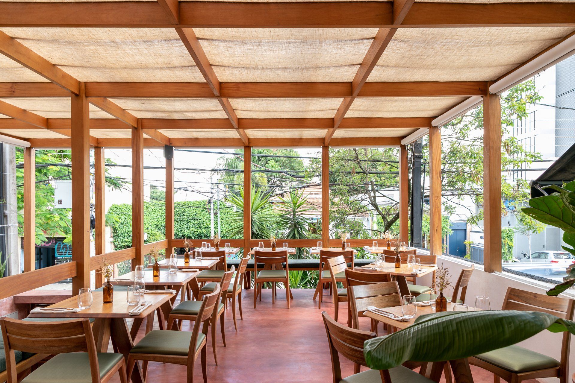 Um restaurante com mesas e cadeiras sob telhado de madeira.