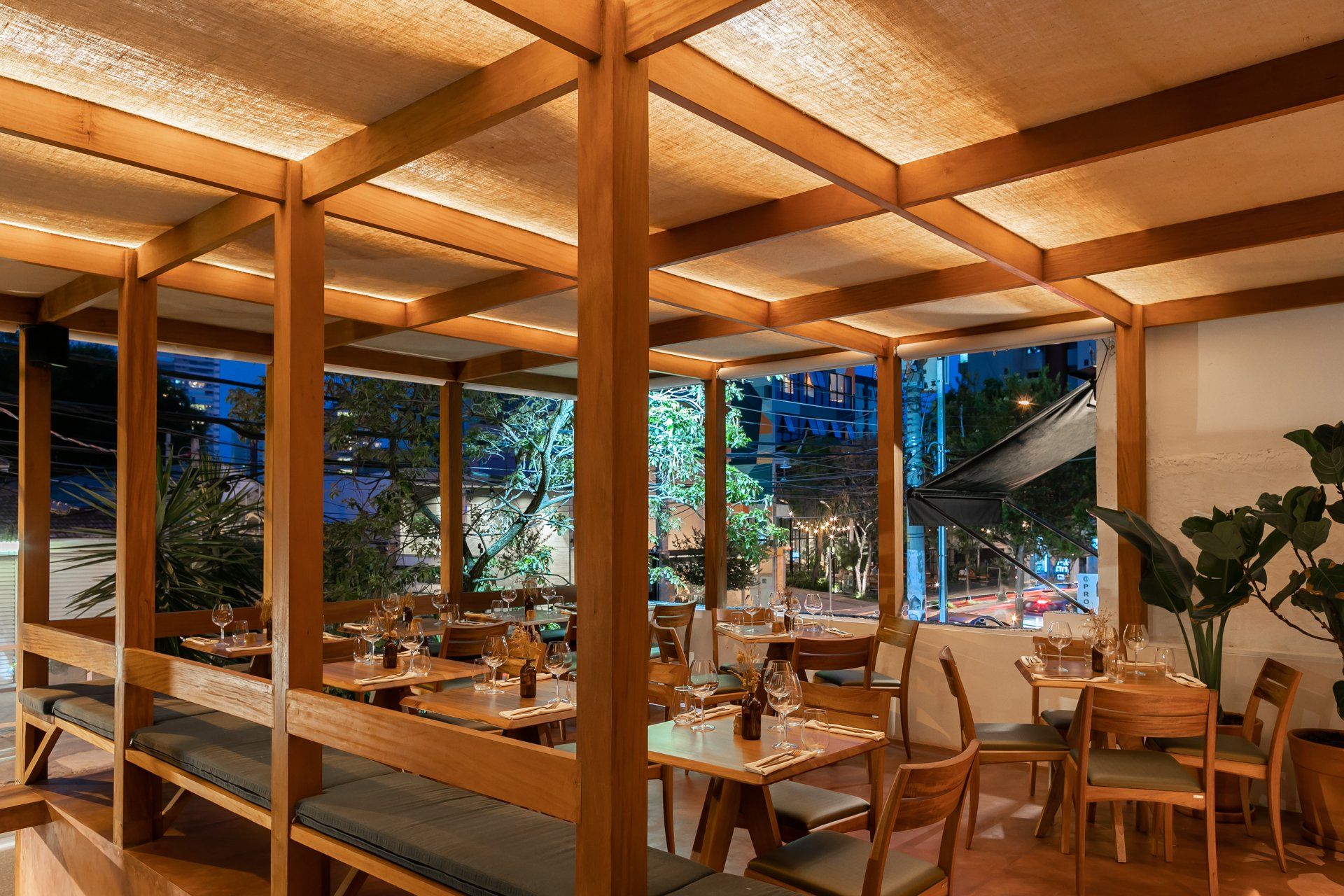 Um restaurante com mesas e cadeiras e teto de madeira.