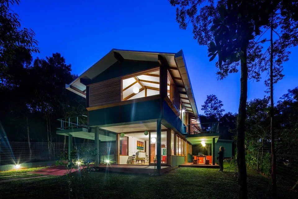 Uma casa está iluminada à noite no meio de uma floresta