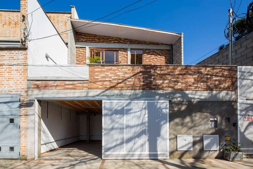 A frente de uma casa com garagem e parede de tijolo.