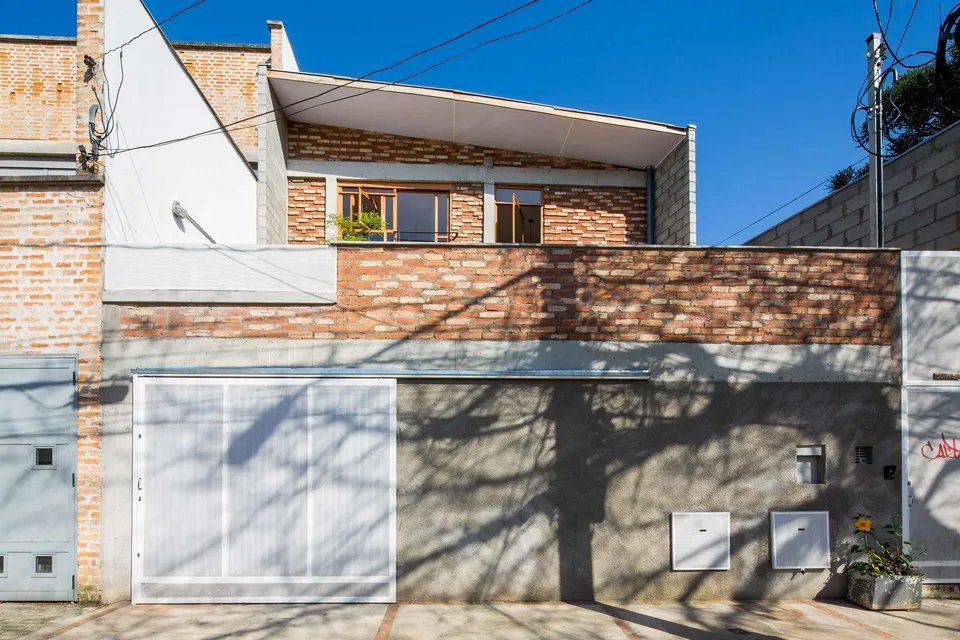 Uma casa de tijolos com uma porta de garagem branca e um céu azul ao fundo.