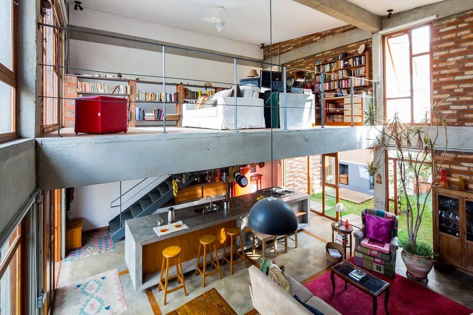 Uma sala com sofá, mesa, cadeiras e cozinha.