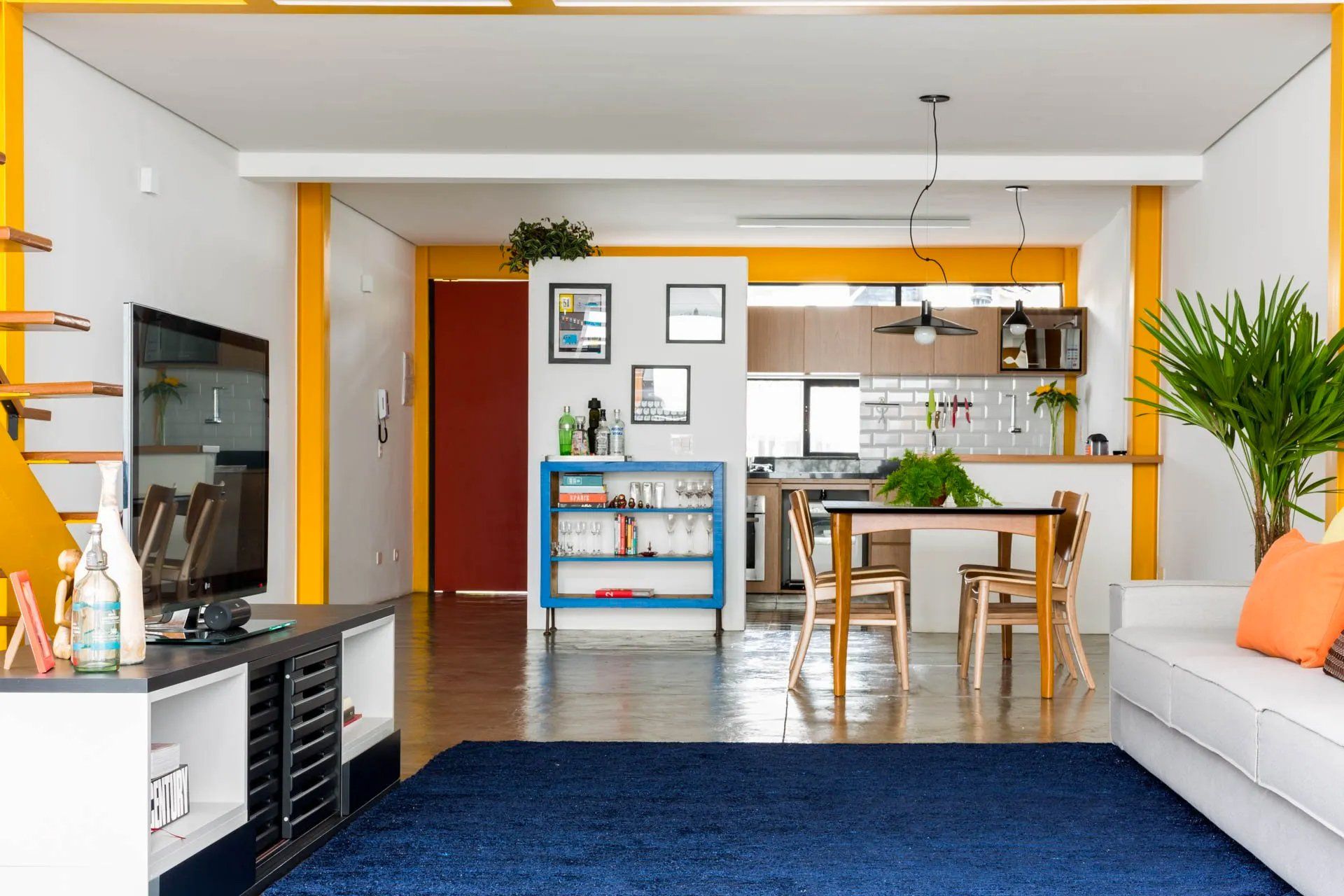 Uma sala com sofá, mesa, cadeiras e televisão.