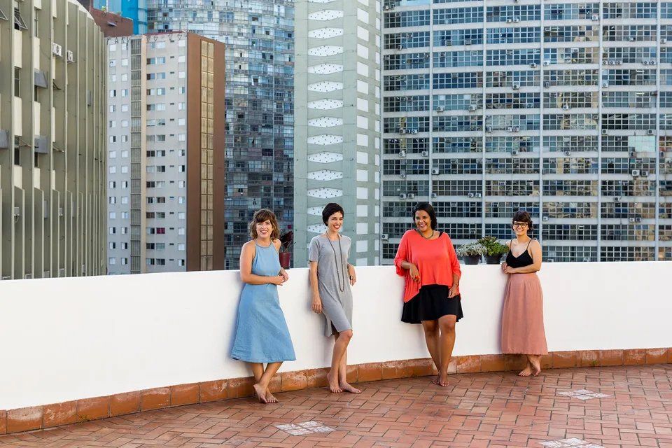Um grupo de mulheres está em uma varanda com vista para uma cidade.