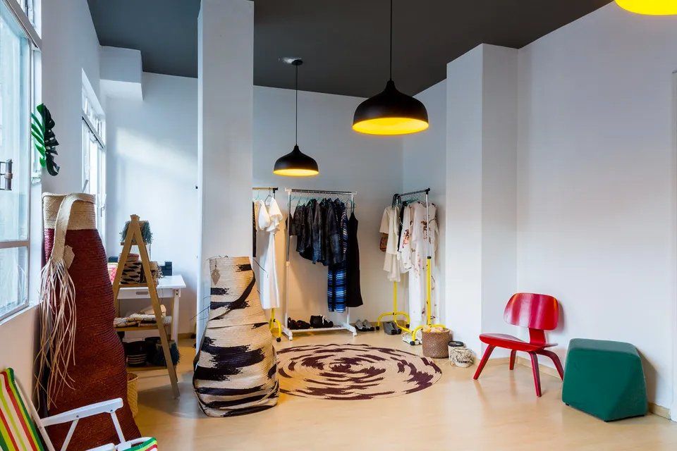Um quarto com roupas penduradas em cabides e cadeiras