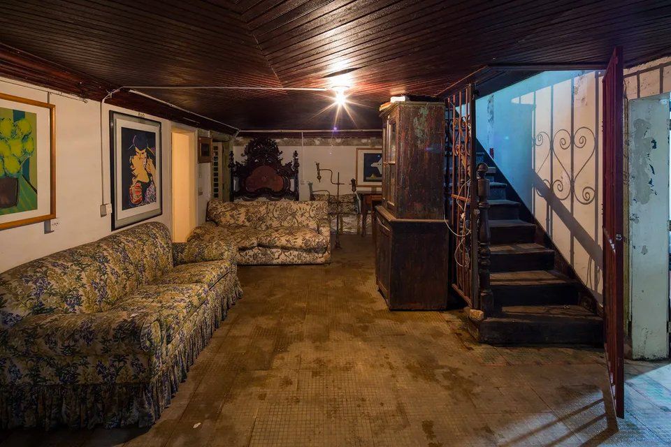 Uma sala de estar com sofá, cadeiras e escadas.