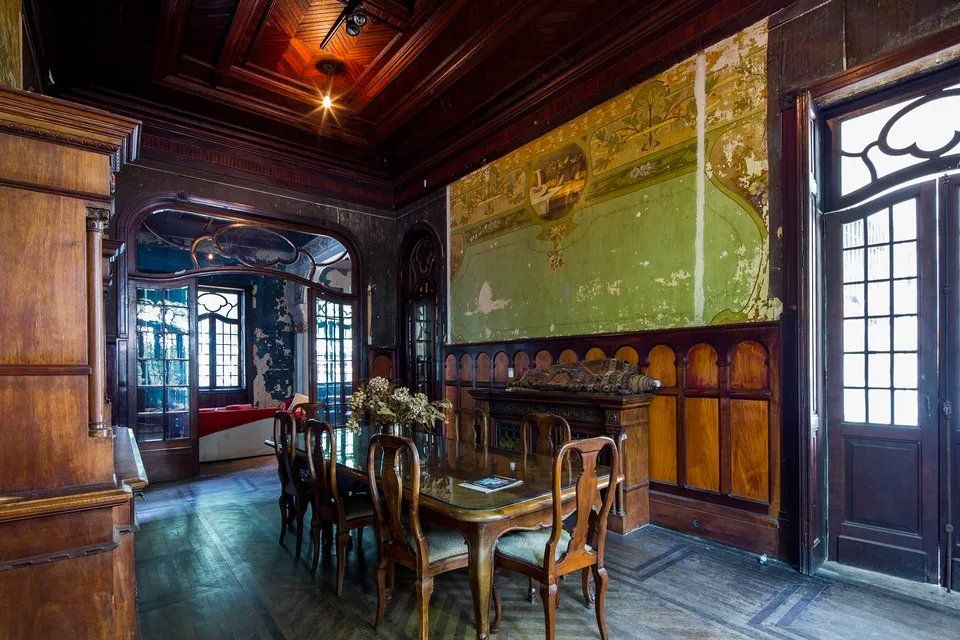 Uma sala de jantar com mesa e cadeiras e um grande quadro na parede.