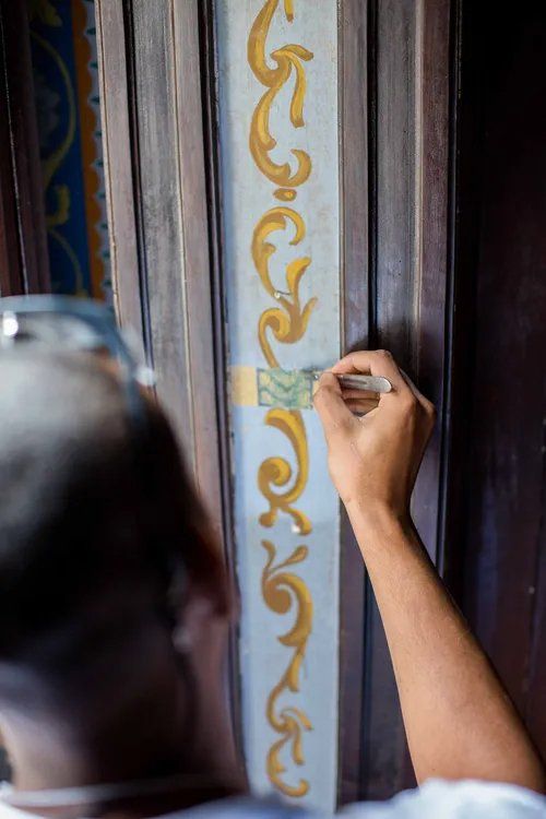 Um homem está pintando um desenho em uma porta de madeira.