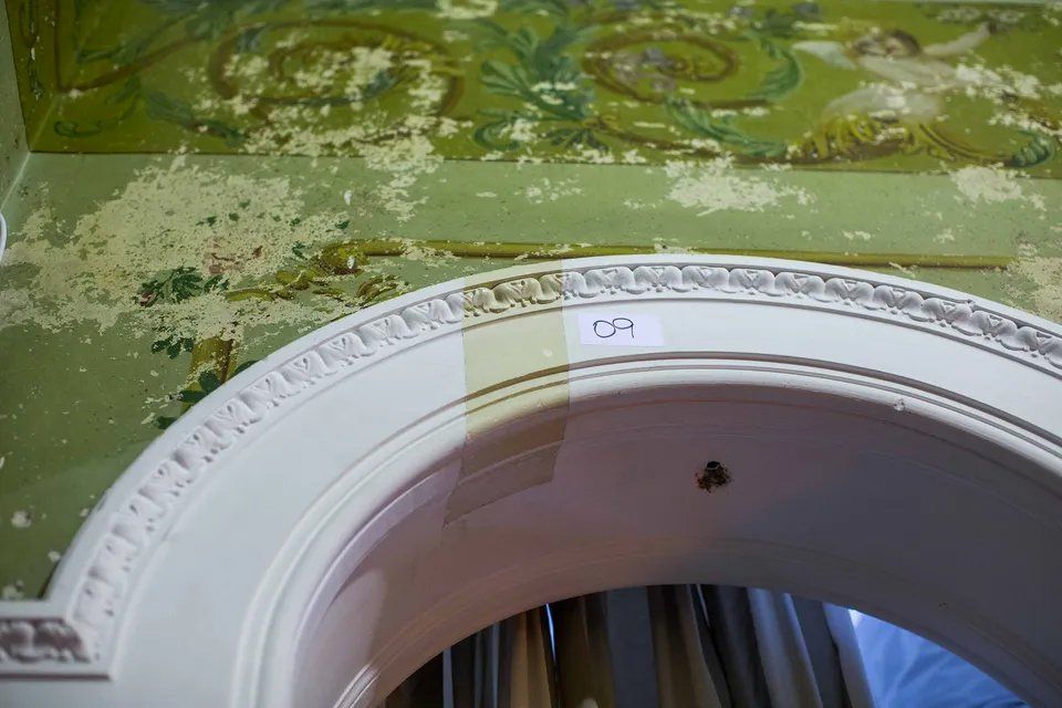 Um arco branco em uma sala com teto verde.
