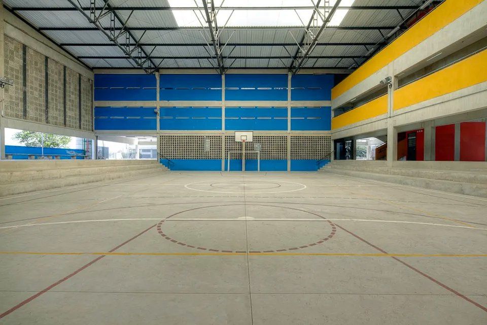 Uma quadra de basquete vazia com paredes azuis e amarelas