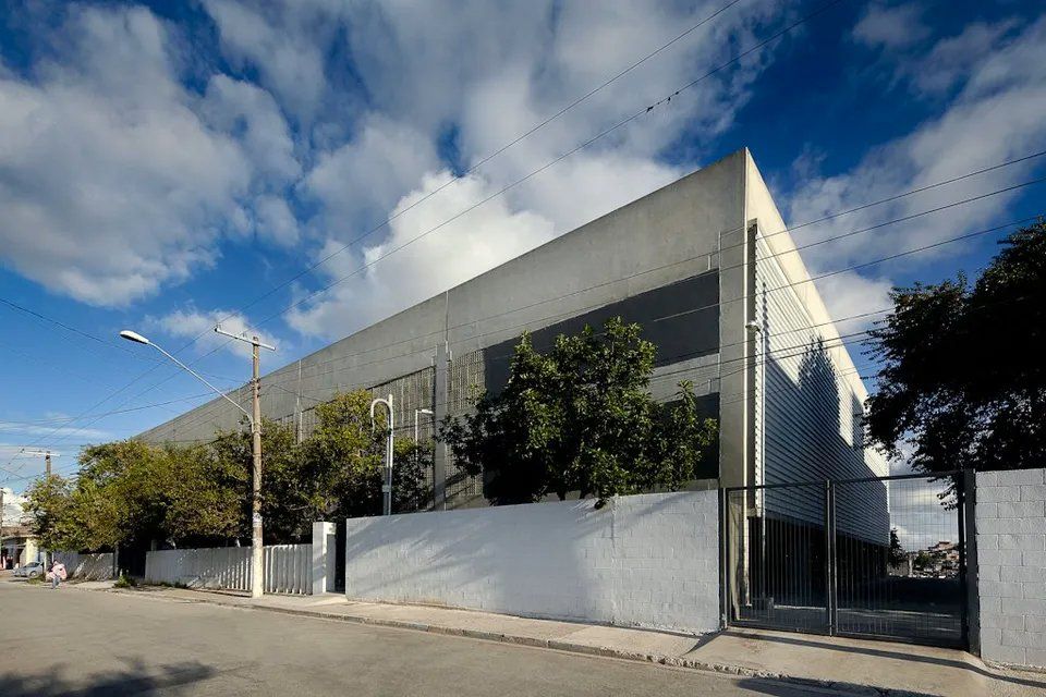 Um grande edifício com uma cerca e árvores na frente