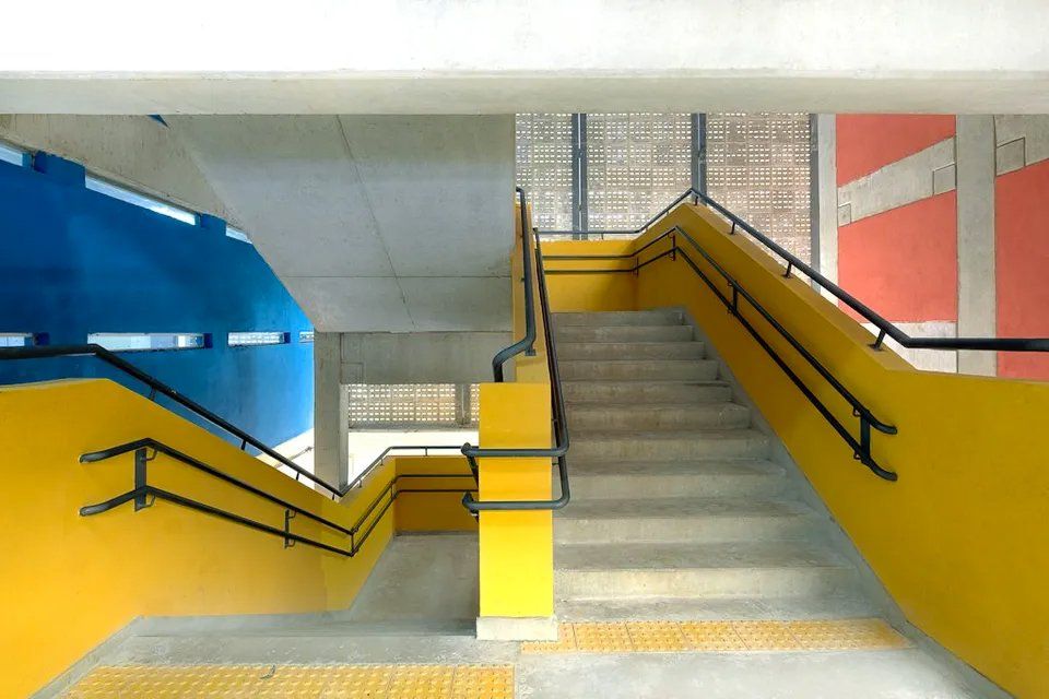 Um conjunto de escadas com paredes amarelas e grades pretas
