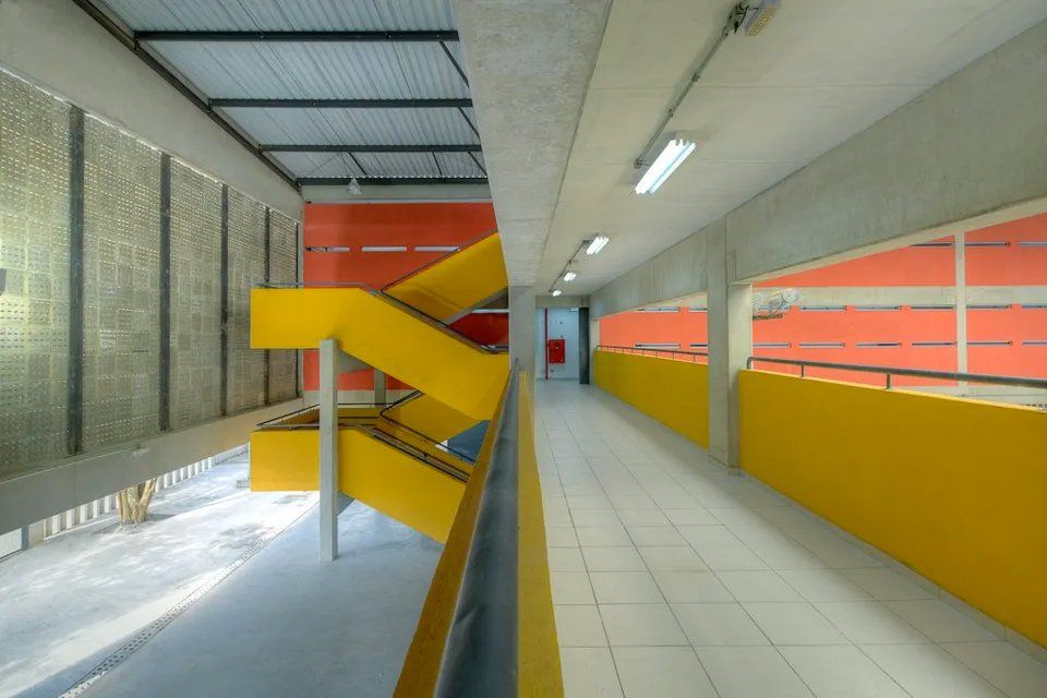 Um longo corredor com corrimão amarelo e escadas