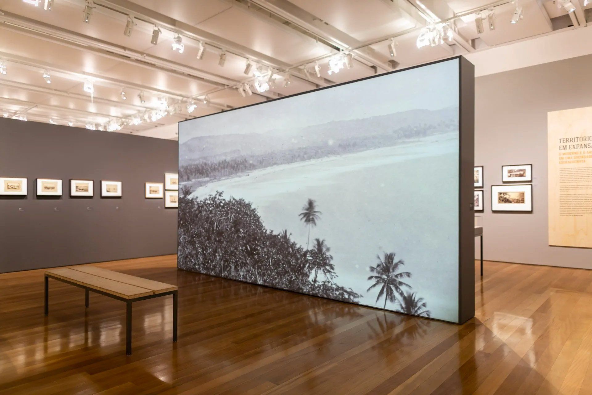 Uma grande parede com a foto de uma praia em um museu.
