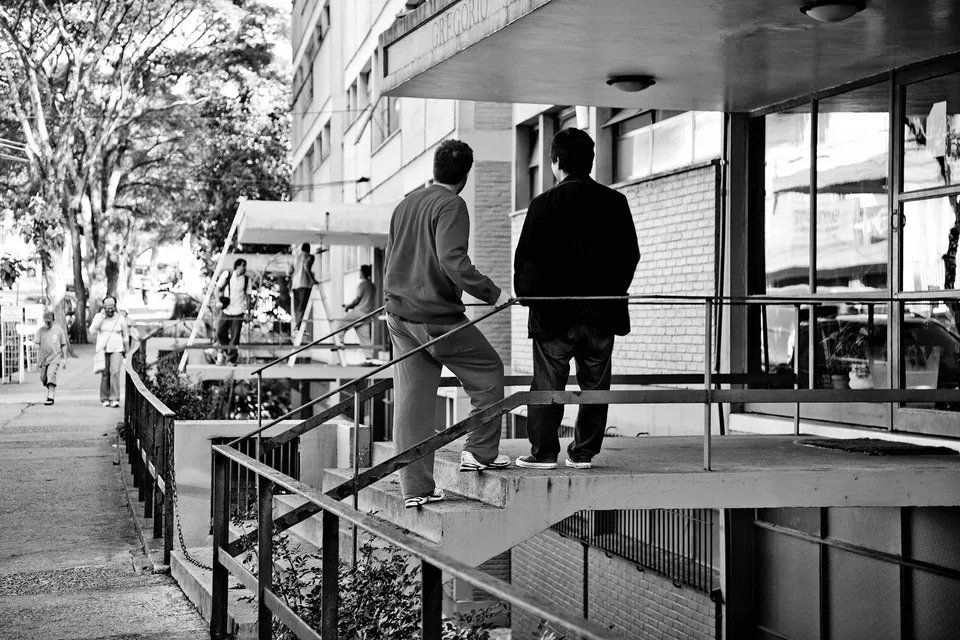 Dois homens estão em uma varanda conversando entre si.