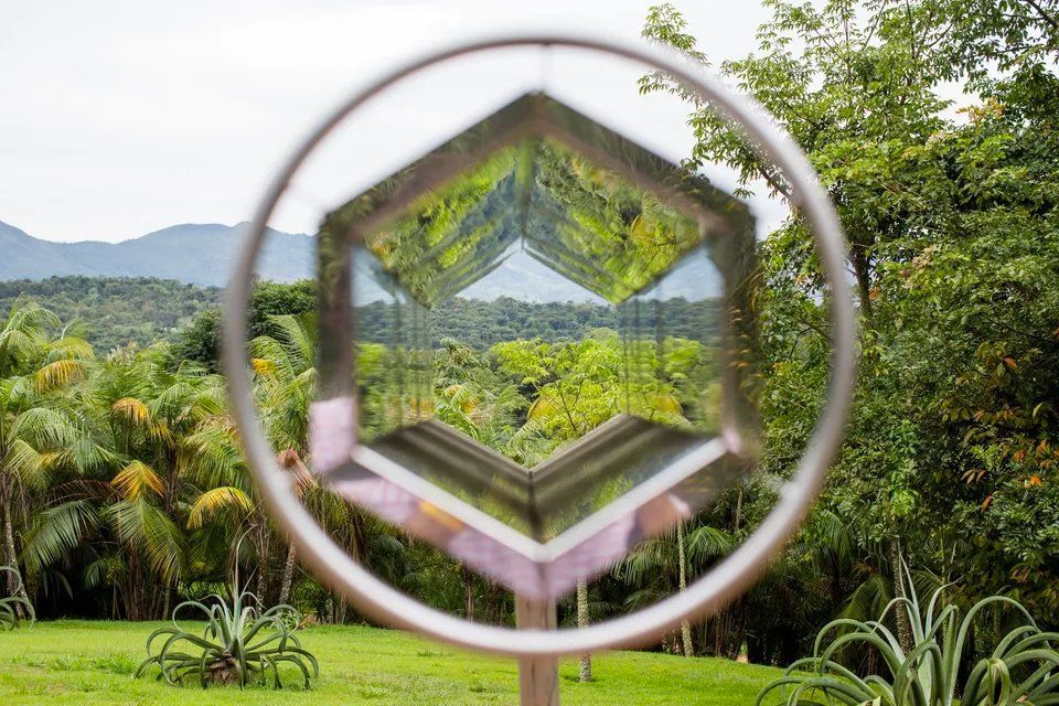 Uma pessoa está olhando através de um caleidoscópio para um campo verdejante.