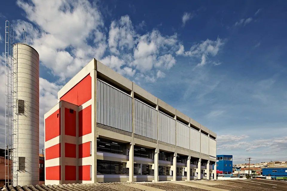 Um grande edifício vermelho e branco com uma torre de água na frente.